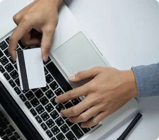 Hands typing on a laptop with a card, processing labour cancellation in UAE online.