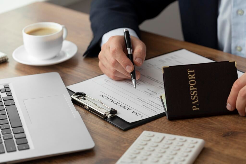 Person filling out UAE Blue Visa application form with passport and laptop on desk